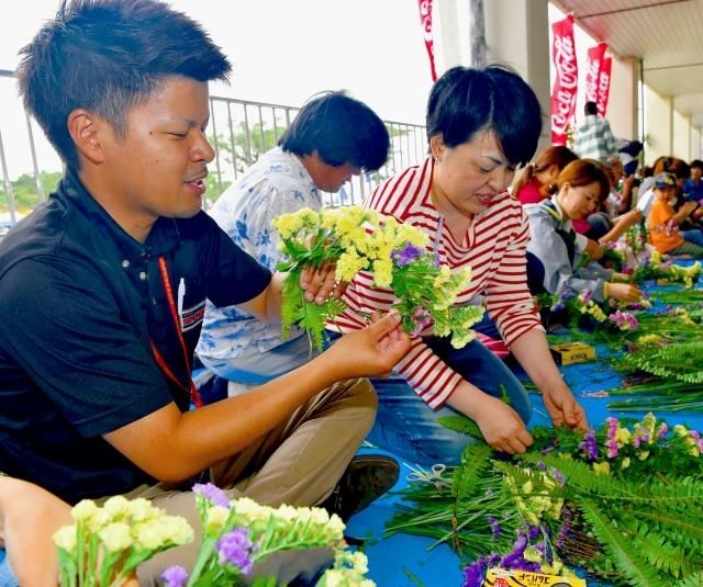 心を込めて花冠を作るボランティア＝１８日午後、宮古島市総合体育館前