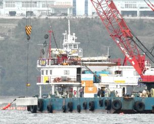 クレーンでコンクリートブロックを海中に投下する作業船＝２月２４日、名護市辺野古沖