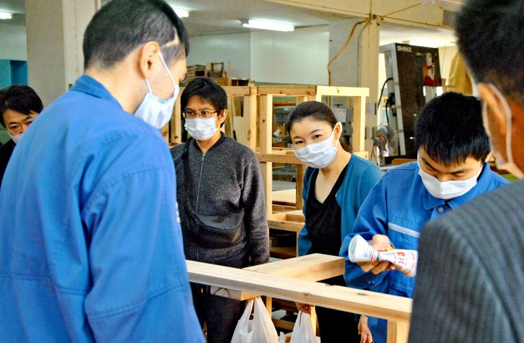 木工の作業をする生徒を見つめる企業担当者ら＝１６日、うるま市・沖縄高等特別支援学校
