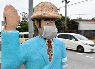 八重瀬町富盛で交通安全を見守る「おまわりさん？」。コロナ感染防止対策もバッチリ。マスク着用で目を光らす＝１７日