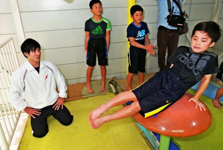 子どもたちのフォームをチェックしながら指導する安里圭亮（左）＝うるま市・ケンケン体操教室（古謝克公撮影）