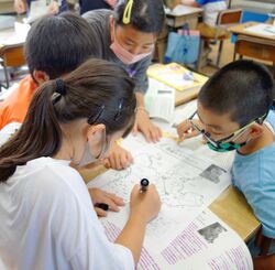 沖縄戦の証言を読んで、避難ルートを地図に書き込む児童たち＝２２日、南風原小学校