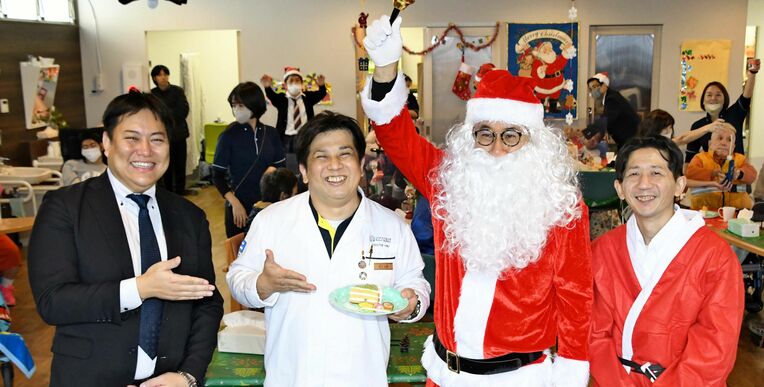 ケーキを贈呈した砂川直樹さん（左から２人目）とセンターを運営する「あかね会」の宇良龍太さん（左端）＝２０２２年１２月２２日、糸満市糸満