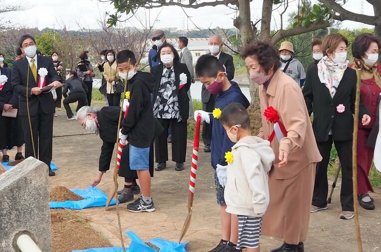 川沿いの遊歩道で植樹する参加者たち＝６日、うるま市石川