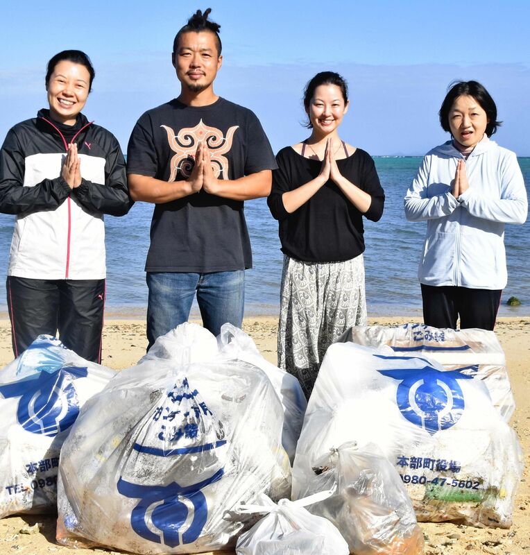 海辺でのヨガとごみ拾いを続ける松岡弥生さん（右から２人目）、和洋さん（同３人目）夫妻と参加者ら＝２０２０年１２月２７日、本部町