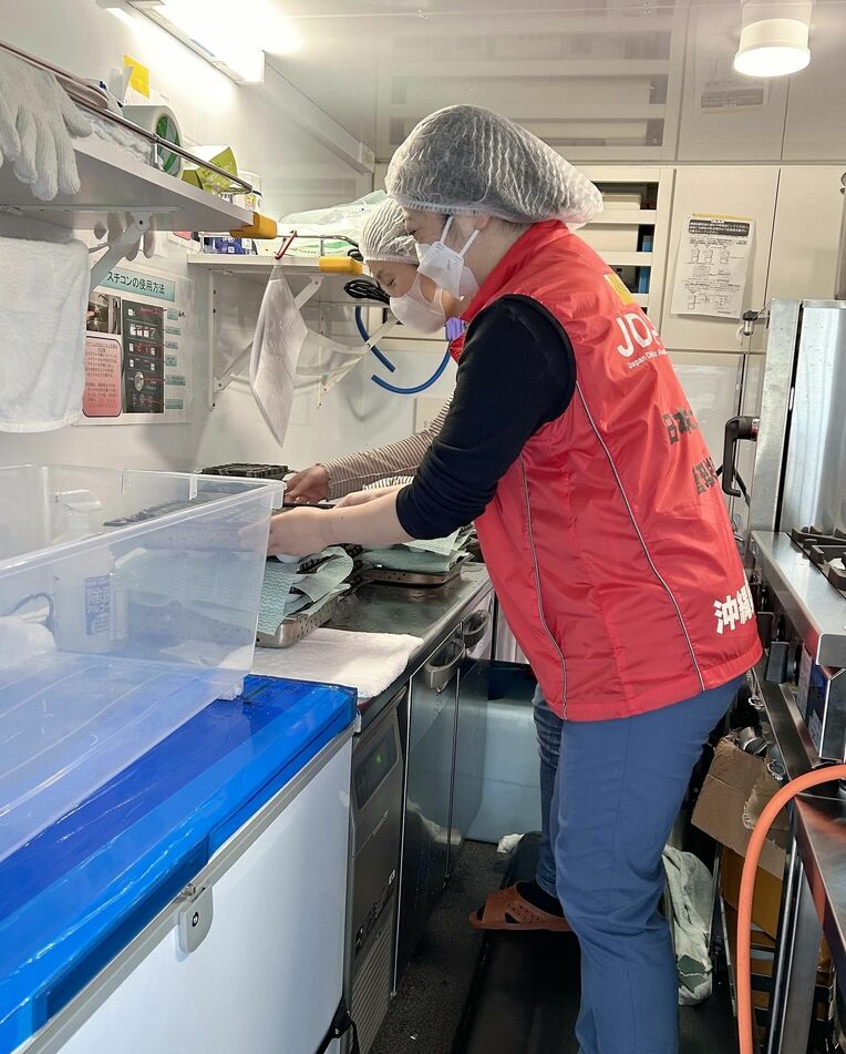 避難所に設置されたキッチンカーで、弁当を温める手順について説明する稲垣夏子さん（手前）ら＝２月１８日、金沢市・いしかわ総合スポーツセンター（提供）